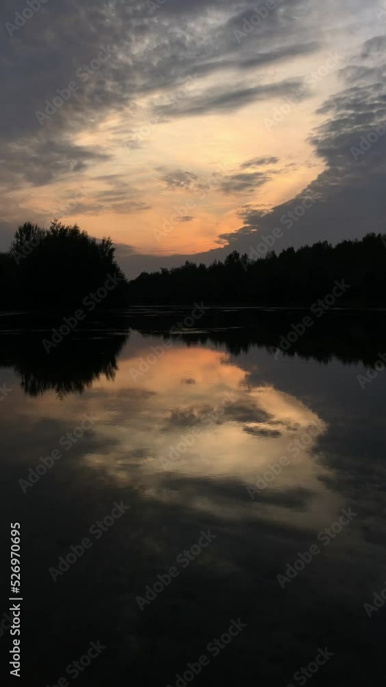 Dramatic sky with sun shines through gray clouds reflected at lake water at night Dramatic sky with sun shines through gray clouds reflected at lake water at night