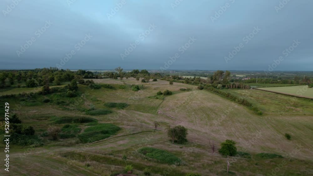 Aerial shot flying through flat meadows in Belgium during sunrise with dark clouds Aerial shot flying through flat meadows in Belgium during sunrise with dark clouds