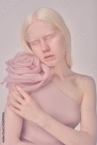 Portrait of beautiful elegant albino girl with elegant dress with big flower accessory posing at camera