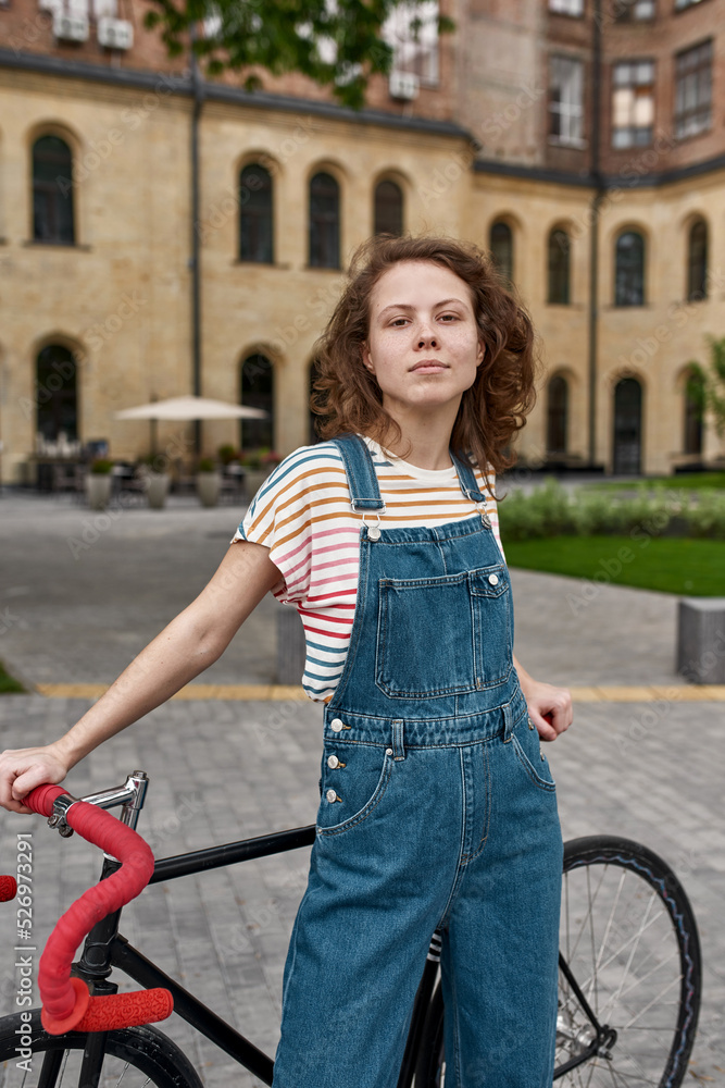Girl with bicycle on city square looking at camera Girl with bicycle on city square looking at camera