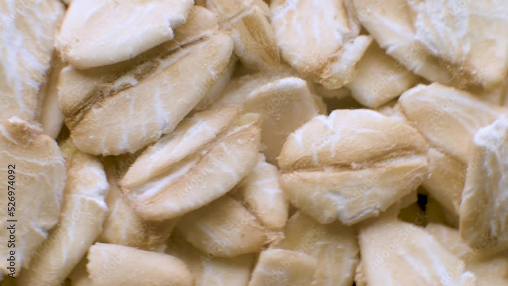 Close-Up. Uncooked Oat Flakes Rotating - Macro. Scattered Dry and Raw Oat Flakes Healthy Breakfast and Diet Eating Ingredients Close-Up. Uncooked Oat Flakes Rotating - Macro. Scattered Dry and Raw Oat Flakes Healthy Breakfast and Diet Eating Ingredients