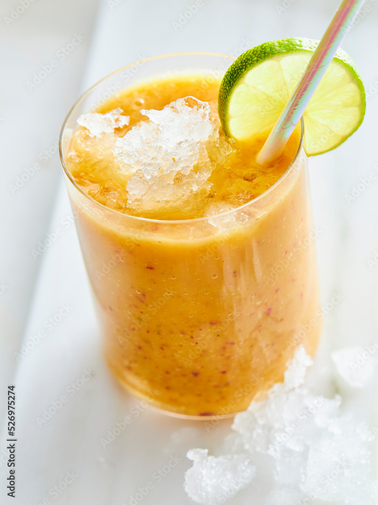 Fresh fruit juice with ice, a slice of lime and straw