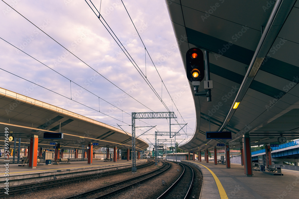 Railway traffic light, red and yellow light stop, passenger train station, platform, railway background, early morning, cloudy sky over the railway, rail traffic, close-up