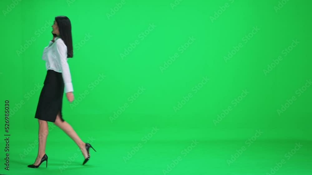 Businesswoman in a suit walks on a green background and talking on a mobile phone, chroma key template. Businesswoman in a suit walks on a green background and talking on a mobile phone, chroma key template.