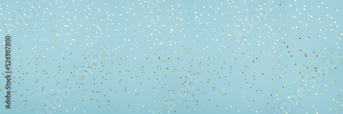 Star shaped shining golden confetti on light blue background. Sparkle sequins. Web banner with copy space