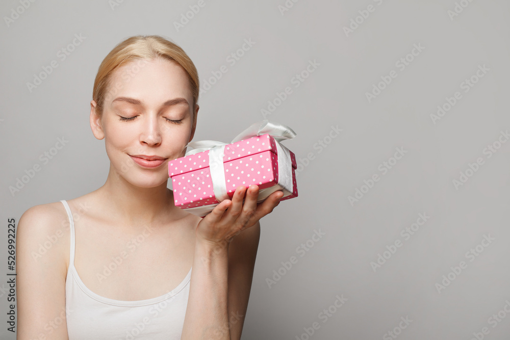 Young pretty smiling woman holding pink gift box and looking at camera on white background Young pretty smiling woman holding pink gift box and looking at camera on white background