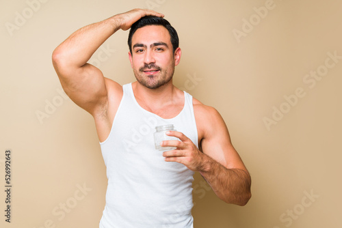 Attractive young man using hair products while grooming to go out