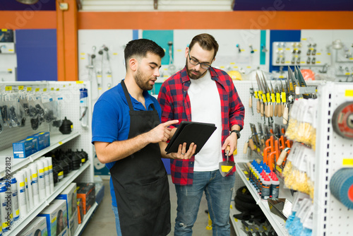 Vászonkép Attractive employee looking for a product with a customer at the hardware store