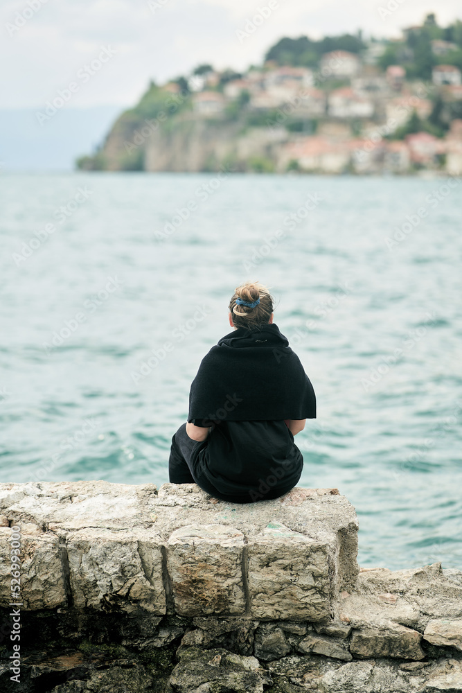 A girl sitting and admiring the view of the old town of Ohrid from the lake in Macedonia. View from the back. High quality photo A girl sitting and admiring the view of the old town of Ohrid from the lake in Macedonia. View from the back. High quality photo