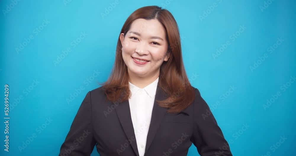 Portrait of Asian happy smile businesswoman doing arranged black suit isolated on blue background Portrait of Asian happy smile businesswoman doing arranged black suit isolated on blue background
