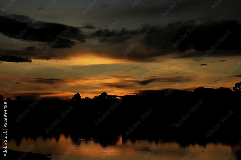 Sunset Paradise with red and blue sky, cloud, village and reflection on the river. Nature background concept with copy space, low key.
