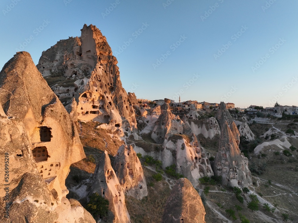 Aerial view of natural rock formations in the sunset, valley with cave houses in Cappadocia, Turkey. Natural landscape city lights at the night.