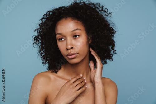 Shirtless black woman touching her skin while posing on camera