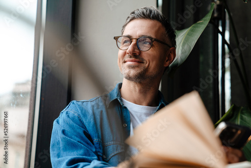 Portrait of adult handsome smiling man looking out the window
