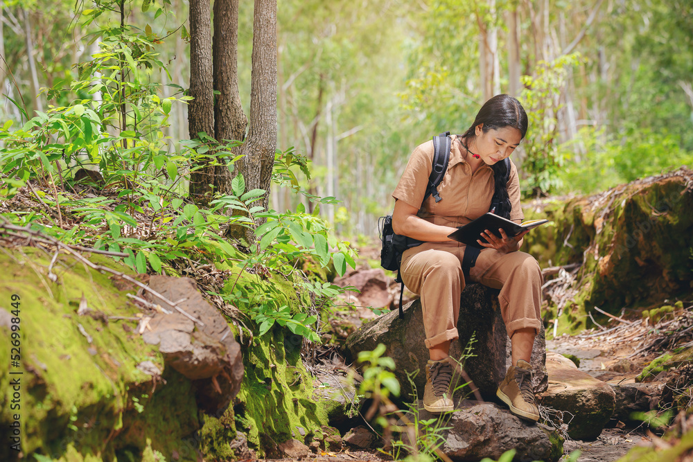 Biologist or botanist recording information about tropical plants in forest. The concept of hiking to study and research botanical gardens by searching for information.	