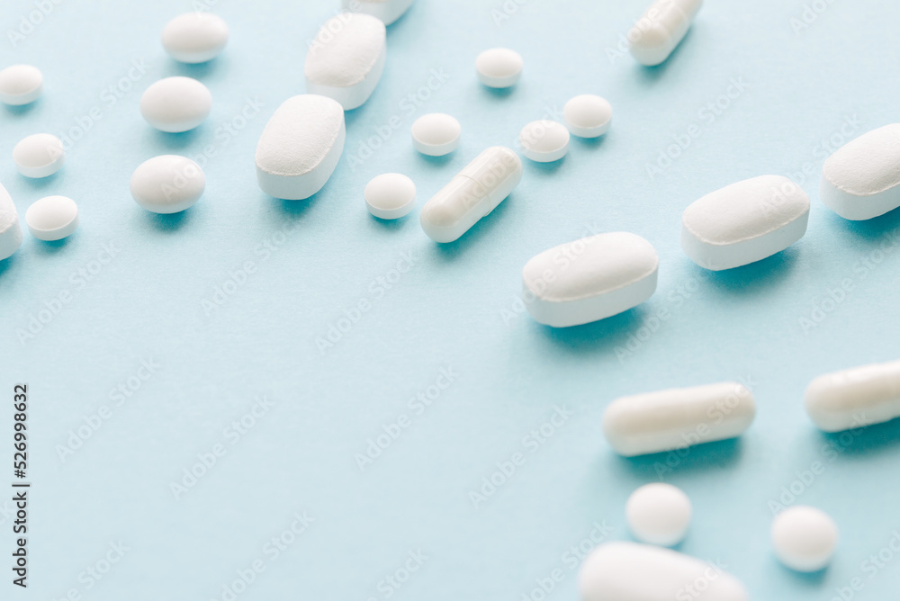Scattered white pills on blue table. Mock up for special offers as advertising, web background or other ideas. Medical, pharmacy and healthcare concept. Copy space. Empty place for text or logo.
