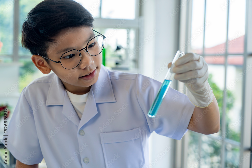 Asian boy researches blue liquid in chemistry lesson at laboratory