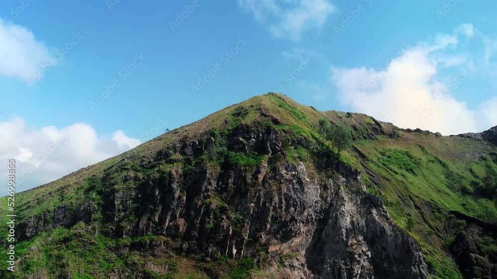 Batur volcano crater on Bali Island. With green forests on the volcano. Drone view.