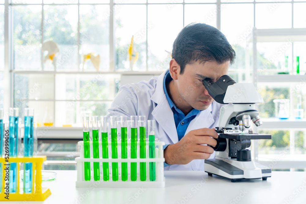 Young male researcher analyzing liquid in tube at laboratory Young male researcher analyzing liquid in tube at laboratory
