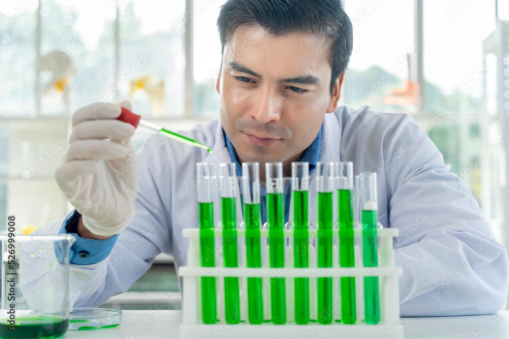 Young male researcher analyzing liquid in tube at laboratory Young male researcher analyzing liquid in tube at laboratory