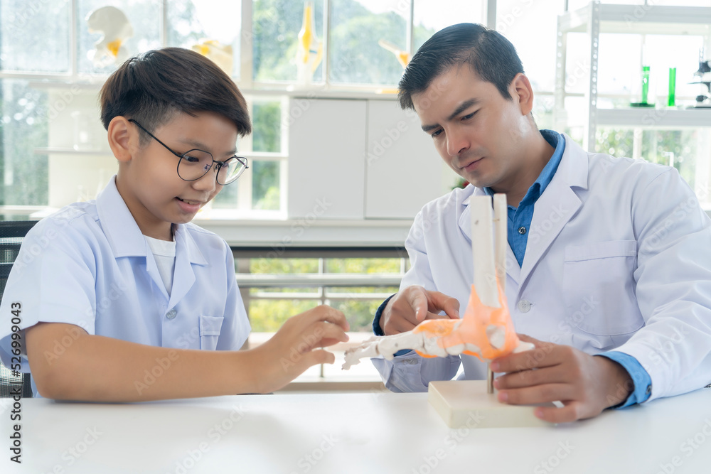 Obraz premium Young teacher and student boy learning anatomy of the human foot