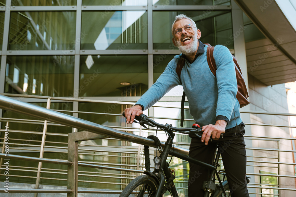 Mature man with beard laughing while riding his bicycle