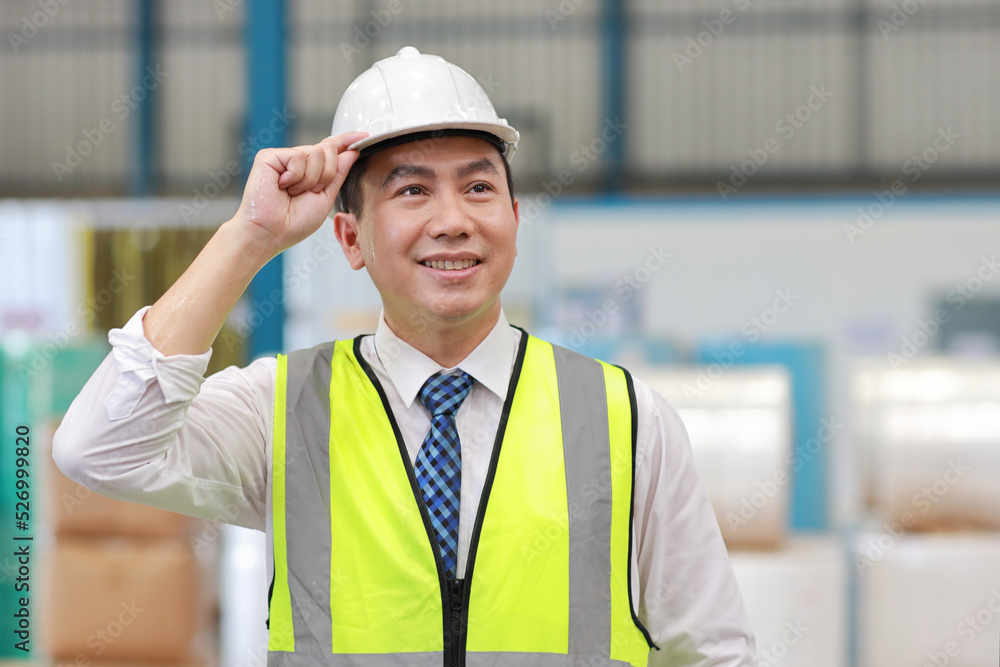 Asian engineering worker man portrait standing and holding hardhat with happy smiling face with confident and blurred large warehouse background Asian engineering worker man portrait standing and holding hardhat with happy smiling face with confident and blurred large warehouse background