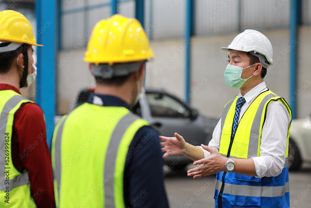 Group of technician engineer and businessman in protective uniform standing and discussing, researching, brainstorming and planning work together with protection mask at industry manufacturing factory Group of technician engineer and businessman in protective uniform standing and discussing, researching, brainstorming and planning work together with protection mask at industry manufacturing factory