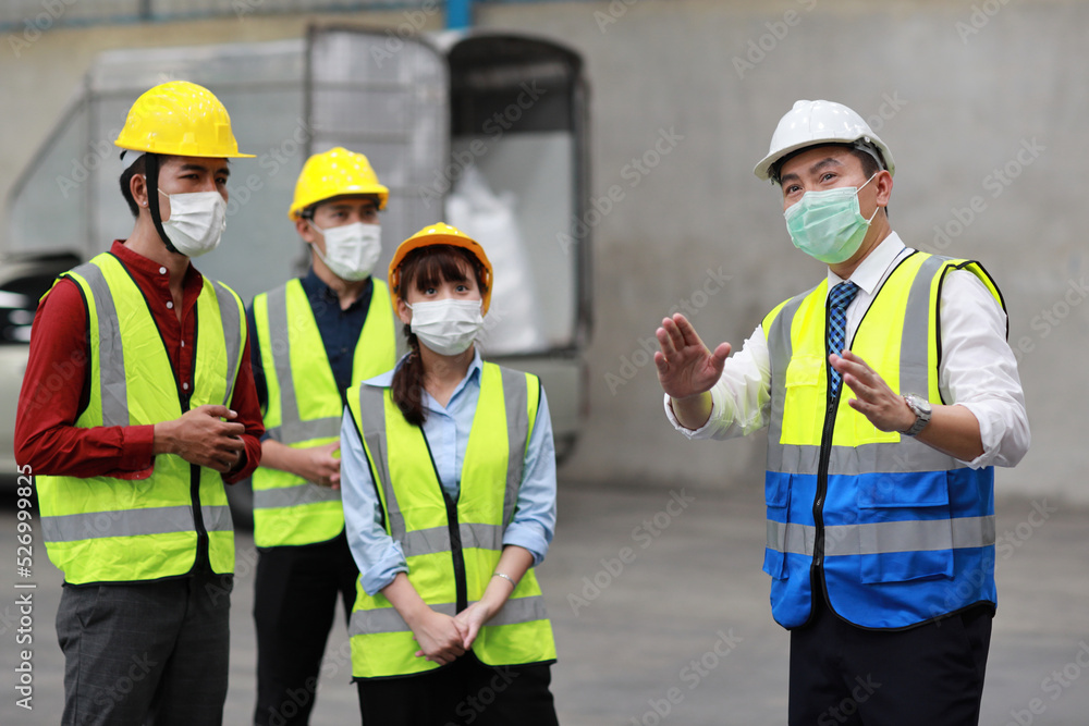 Group of technician engineer and businessman in protective uniform standing and discussing, researching, brainstorming and planning work together with protection mask at industry manufacturing factory Group of technician engineer and businessman in protective uniform standing and discussing, researching, brainstorming and planning work together with protection mask at industry manufacturing factory