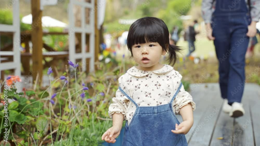 closeup shot curious Asian little girl running toward the camera feeling eagerness while exploring at a farm holiday destination with her parent walking behind closeup shot curious Asian little girl running toward the camera feeling eagerness while exploring at a farm holiday destination with her parent walking behind
