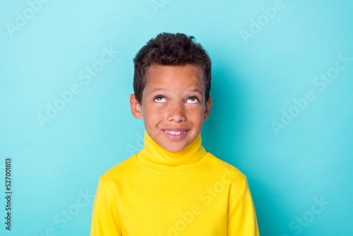 Portrait of positive creative boy toothy smile look interested up empty space isolated on emerald color background