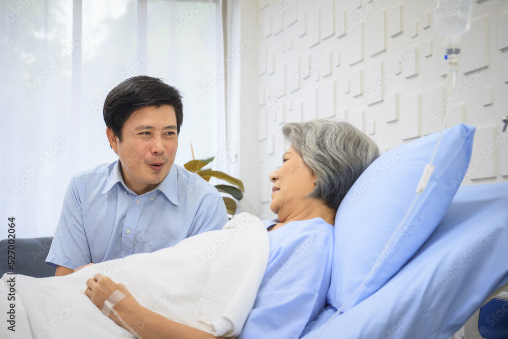 Obraz premium Senior Asian female patient resting on the medical bed in hospital and talking to doctor. 