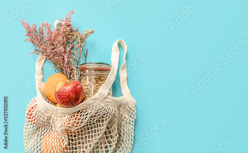 trendy eco friendly organic net bag with some goods isolated over blue background