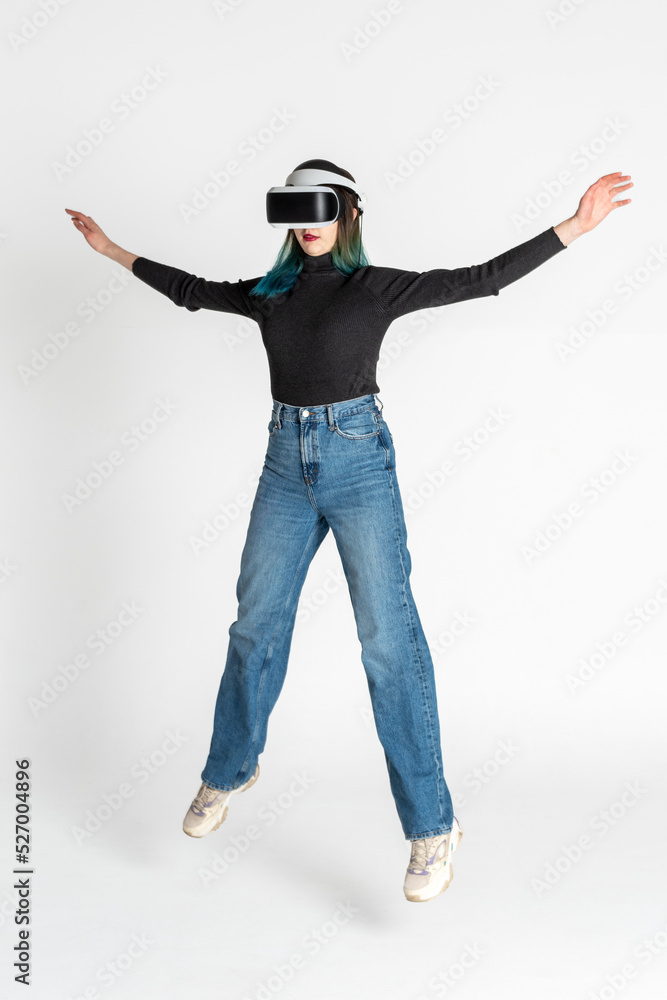 Virtual reality. A teenage girl with blue hair wearing virtual reality glasses watching movies or playing video games jumps, waving her arms. Funny girl looking into VR glasses levitation Virtual reality. A teenage girl with blue hair wearing virtual reality glasses watching movies or playing video games jumps, waving her arms. Funny girl looking into VR glasses levitation