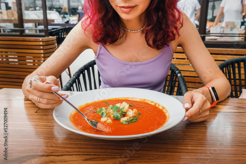 Woman eating delicious tomato soup in cafe or restaurant. Vegetarian cuisine and healthy vegetable diet. Dinner and meal with organic products