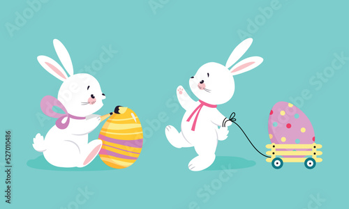 White Easter Bunny Painting Colorful Egg and Pulling Trolley on Blue Background Vector Set