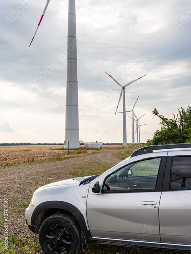 Adyghe wind farm from many towers of wind turbines in field. Towers of wind turbines with rotating blades at sunset against cloudy sky. Close-up. Wind power complex of Rosatom. photo