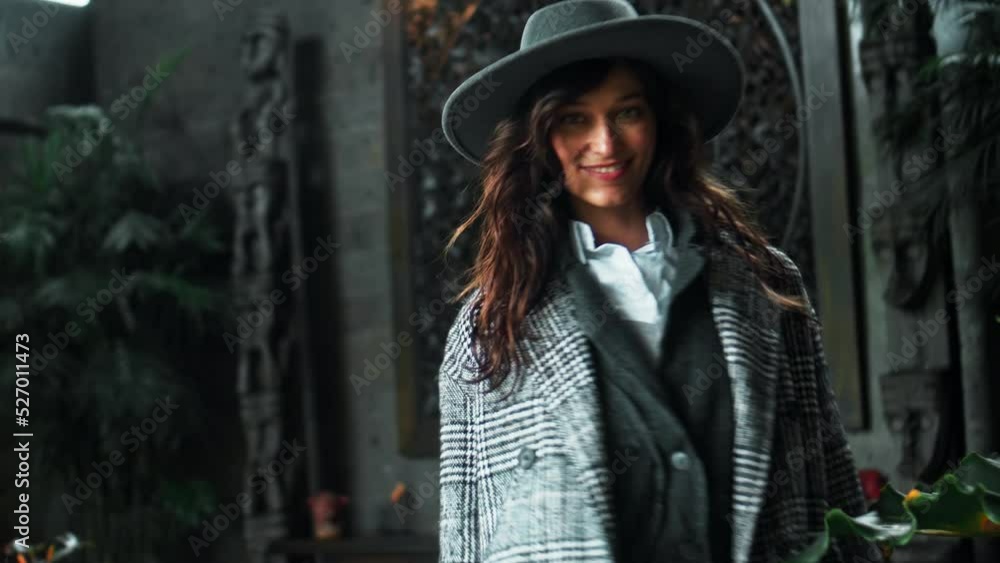 Young European beautiful brunette girl in autumn checked coat and hat sweetly poses on camera Young European beautiful brunette girl in autumn checked coat and hat sweetly poses on camera