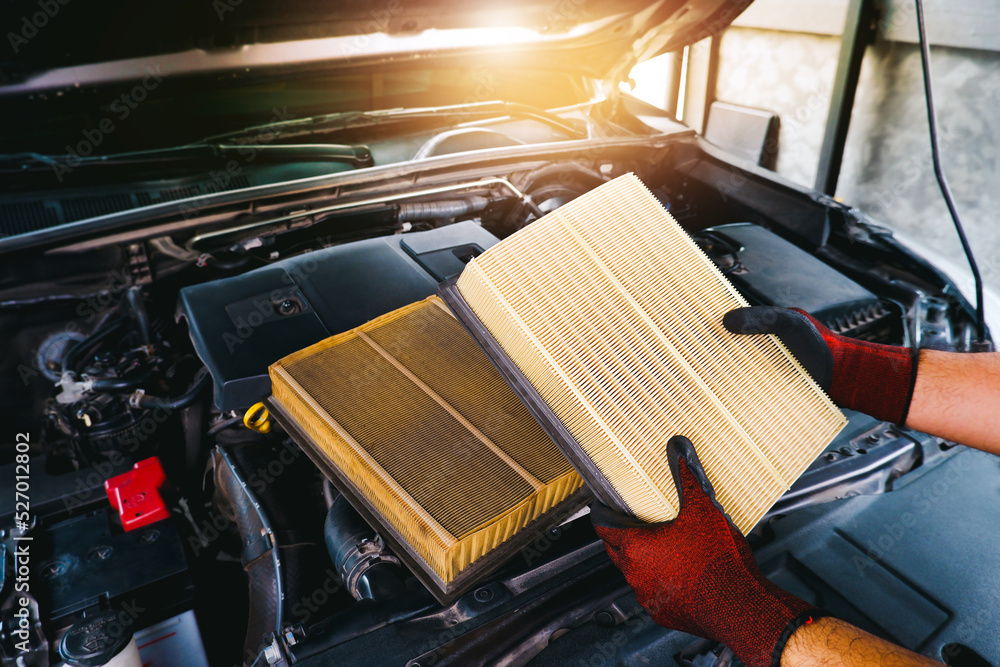 The mechanic holds a new car air filter to replace the old car filter, Automobile maintenance service business concept - obrazy, fototapety, plakaty 