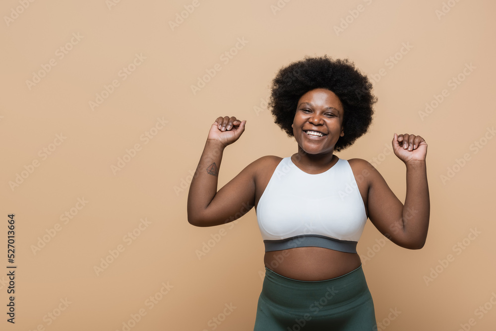 excited african american plus size woman with tattoo isolated on beige. excited african american plus size woman with tattoo isolated on beige.