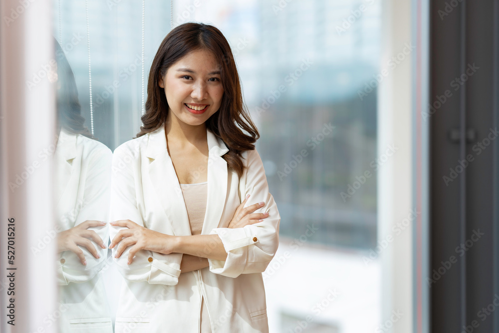 Charming Smiling Asian businesswoman a smile standing and looking at the camera over office background Charming Smiling Asian businesswoman a smile standing and looking at the camera over office background