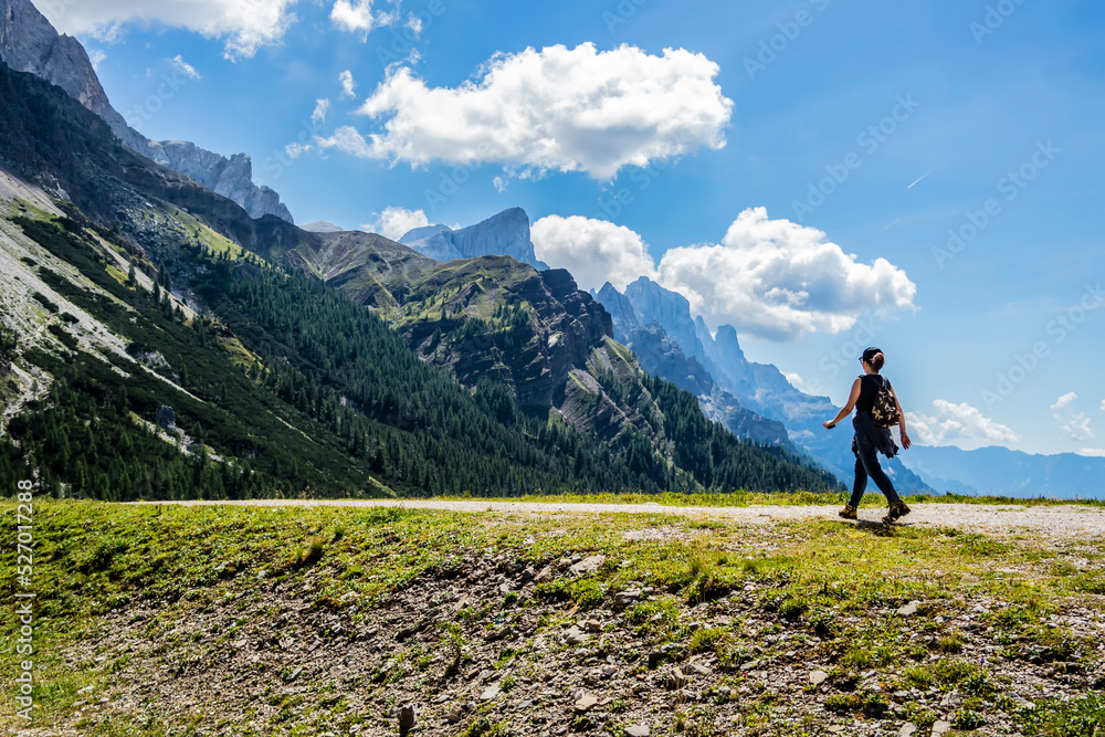 Fototapeta premium Girl walking down a mountain path. San Martino di Castrozza, Trentino Alto Adige - Italy