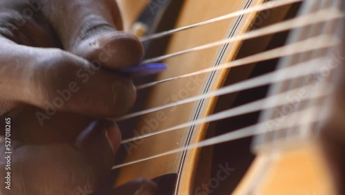 Close shot of black man playing acoustic guitar sitting on chair photo