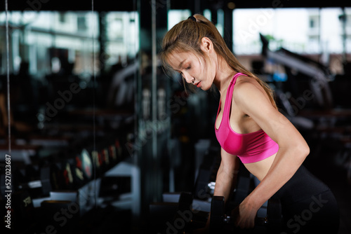 portrait muscular asian women working out with dumbbells in gym