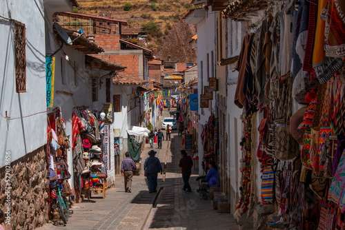 Typical street in the town of Pisac with its colorful stores, mountain view and a beautiful blue sky with clouds, in Peru. © Alberto