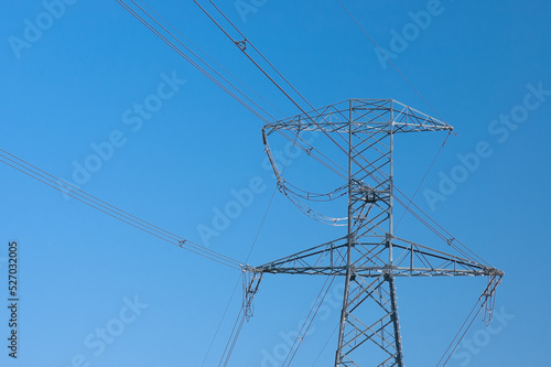 a high-voltage power transmission line, in the photo, a power line support against a blue sky