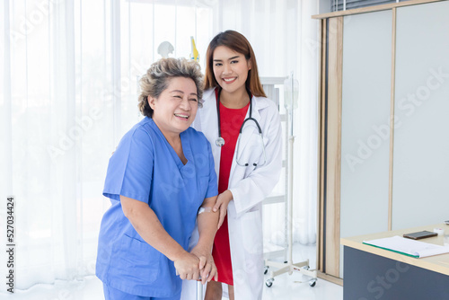 Young attractive Asian doctor is helping an old patient walking, hospital and healthcare concept.