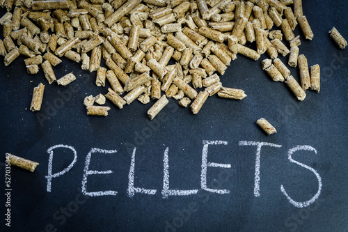 handful of wood pellets for heating on a blackboard with the word pellets handwritten