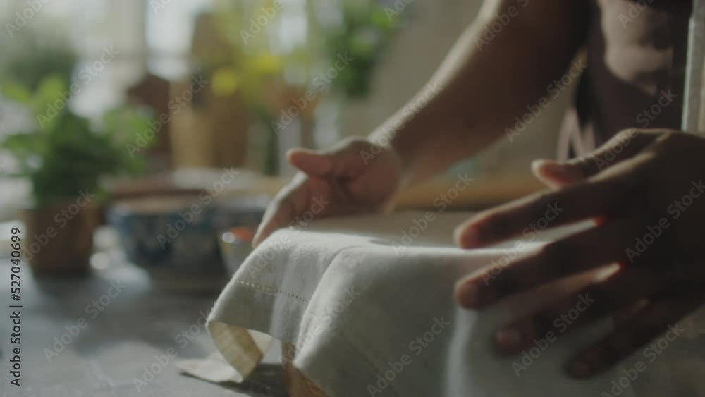 Close up shot of hands of African American woman covering dough with tea towel and taking bowl from kitchen table Close up shot of hands of African American woman covering dough with tea towel and taking bowl from kitchen table