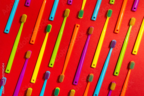 Photo of a modern colorfull toothbrush with differ colors like yellow, violet, blue, green on a red background flat lay style in studio 